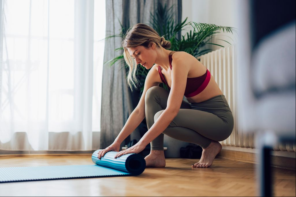 mujer extendiendo la esterilla para hacer pilates en casa